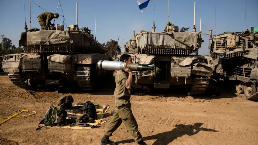 An Israeli soldier carries a tank shell after returning from the Gaza Strip on January 1, 2024 in Southern Border, Israel.

